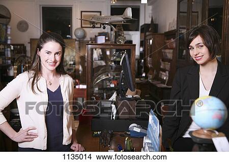 Two women standing on opposites sides of a counter in an antiques shop View Large Photo Image Picture - Two women standing on opposites sides of a counter in an antiques shop. Fotosearch