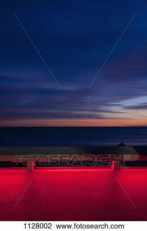 View of the sea at sunset from an illuminated boardwalk View Large Photo Image Stock Image - View of the sea at sunset from an illuminated boardwalk. Fotosearch