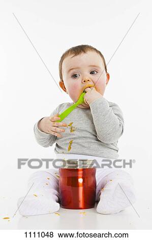 A baby eating food from a container View Large Photo Image Stock Photo - A baby eating food from a container. Fotosearch