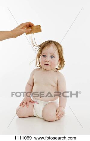 A baby girl having her hair combed View Large Photo Image Stock Photo - A baby girl having her hair combed. Fotosearch