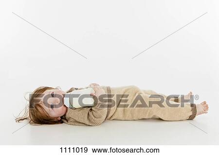 A baby girl lying down with a bottle of milk View Large Photo Image Stock Photo - A baby girl lying down with a bottle of milk. Fotosearch