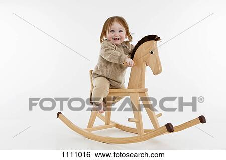 A baby girl on a rocking horse View Large Photo Image Stock Photograph - A baby girl on a rocking horse. Fotosearch