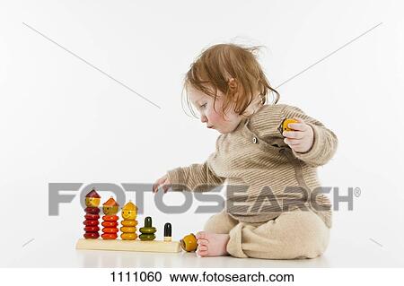 A baby girl playing with a wooden stacking toy View Large Photo Image Stock Image - A baby girl playing with a wooden stacking toy. Fotosearch