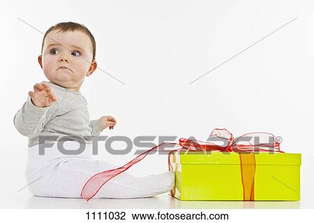 A baby girl sitting with a present View Large Photo Image Stock Image - A baby girl sitting with a present. Fotosearch
