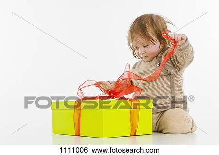 Stock Photograph - A baby girl unwrapping a present. Fotosearch
