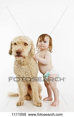 Stock Photo - A baby girl with a dog. Fotosearch