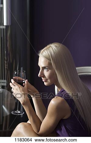 A beautiful young woman holding a glass of red wine View Large Photo Image Picture - A beautiful young woman holding a glass of red wine. Fotosearch