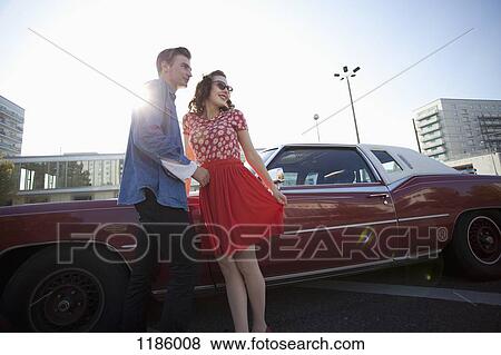 A cheerful rockabilly couple standing next to a vintage car View Large Photo Image Stock Photo - A cheerful rockabilly couple standing next to a vintage car . Fotosearch