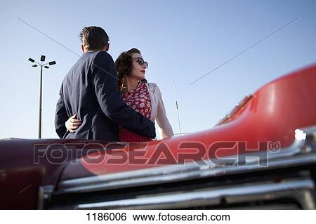 A cool, rockabilly couple with arms around each other by a vintage car View Large Photo Image Stock Photograph - A cool, rockabilly couple with arms around each other by a vintage car. Fotosearch