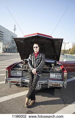 A cool rockabilly guy holding tools leaning against the front of his vintage car, hood up View Large Photo Image Stock Image - A cool rockabilly guy holding tools leaning against the front of his vintage car, hood up. Fotosearch