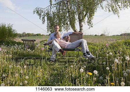 A couple enjoying sunshine and wine on a bench in their backyard View Large Photo Image Stock Image - A couple enjoying sunshine and wine on a bench in their backyard. Fotosearch