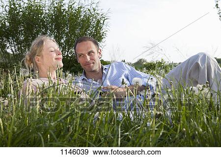 A couple lying in the grass enjoying some red wine View Large Photo Image Stock Photo - A couple lying in the grass enjoying some red wine. Fotosearch