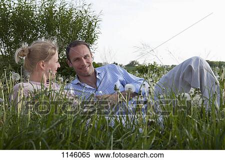 Stock Photography - A couple lying in the grass enjoying some red wine. Fotosearch