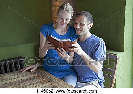 A couple reading a personal organizer together and smiling View Large Photo Image Stock Image - A couple reading a personal organizer together and smiling. Fotosearch