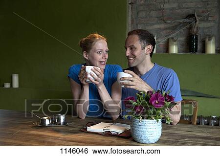 A couple sitting at a dining table with a personal organizer, talking over coffee View Large Photo Image Stock Photograph - A couple sitting at a dining table with a personal organizer, talking over coffee. Fotosearch