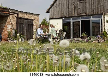 A couple sitting at a table in their backyard talking View Large Photo Image Stock Photo - A couple sitting at a table in their backyard talking . Fotosearch