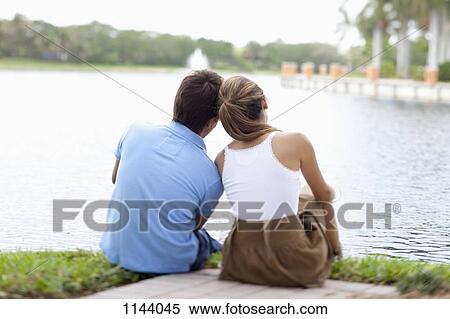 A couple sitting by a lake, rear view View Large Photo Image Stock Photography - A couple sitting by a lake, rear view. Fotosearch