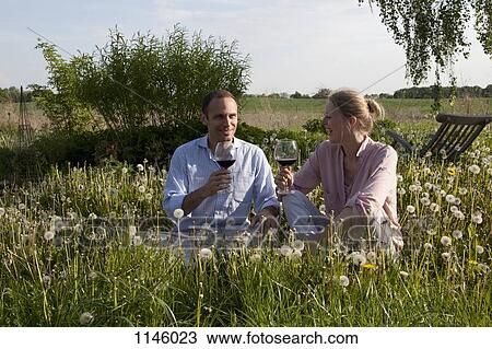 A couple sitting in the grass enjoying some red wine View Large Photo Image Stock Image - A couple sitting in the grass enjoying some red wine. Fotosearch