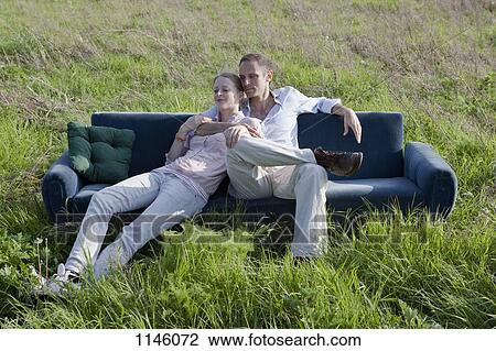 A couple sitting on a sofa in a field of grass View Large Photo Image Stock Image - A couple sitting on a sofa in a field of grass. Fotosearch