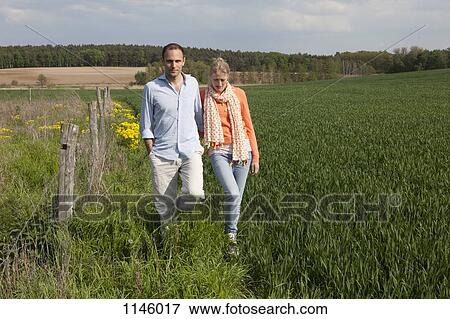 A couple walking in a field side by side View Large Photo Image Stock Photo - A couple walking in a field side by side. Fotosearch