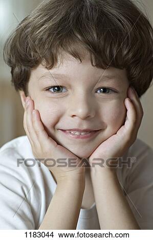 Picture - A cute, cheerful boy leaning on his hands. Fotosearch