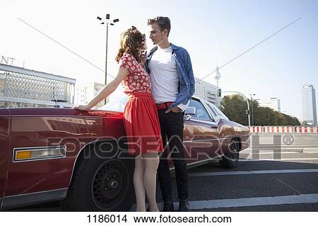 A flirtatious rockabilly couple standing next to a vintage car, Berlin, Germany View Large Photo Image Picture - A flirtatious rockabilly couple standing next to a vintage car, Berlin, Germany. Fotosearch