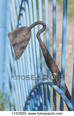 Stock Image - A garden hoe leaning on a gate. Fotosearch