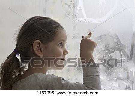 A girl drawing in condensation on glass View Large Photo Image Stock Photography - A girl drawing in condensation on glass. Fotosearch