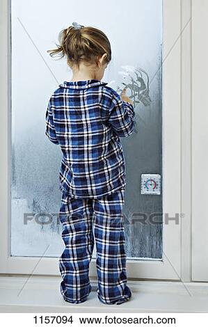 A girl dressed in pajamas and drawing in condensation on glass View Large Photo Image Picture - A girl dressed in pajamas and drawing in condensation on glass. Fotosearch