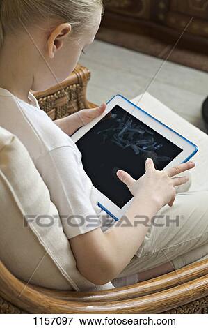 A girl sitting with a digital tablet View Large Photo Image Stock Photo - A girl sitting with a digital tablet. Fotosearch
