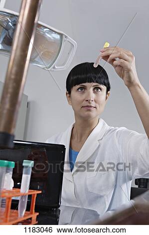 Stock Photograph - A lab technician examining a test tube full of liquid. Fotosearch