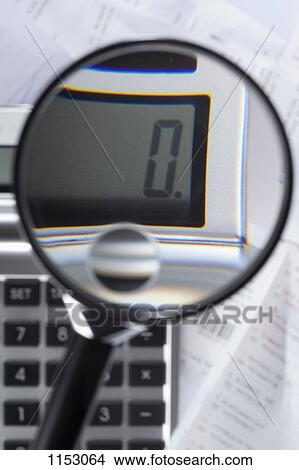 Picture - A magnifying glass magnifying a zero on a calculator on top of paperwork. Fotosearch