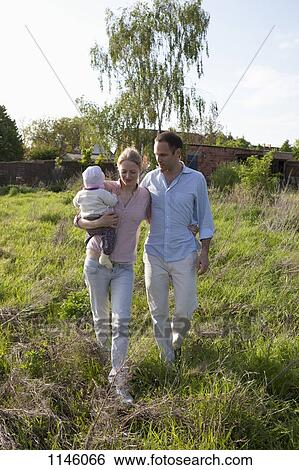 A man and a woman holding a baby walking in back of their country house View Large Photo Image Stock Photograph - A man and a woman holding a baby walking in back of their country house. Fotosearch