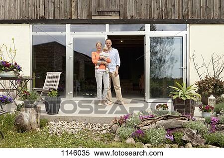 A man and a woman holding a baby standing on the patio in front of their house View Large Photo Image Stock Photography - A man and a woman holding a baby standing on the patio in front of their house. Fotosearch