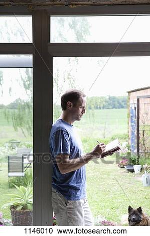 A man leaning against a doorway in his house writing in a journal View Large Photo Image Stock Image - A man leaning against a doorway in his house writing in a journal. Fotosearch