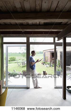 A man leaning against a doorway in his house writing in a journal View Large Photo Image Stock Photo - A man leaning against a doorway in his house writing in a journal. Fotosearch