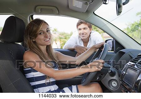 A man leaning in car window smiling at girlfriend in the driver's seat View Large Photo Image Stock Image - A man leaning in car window smiling at girlfriend in the driver's seat. Fotosearch