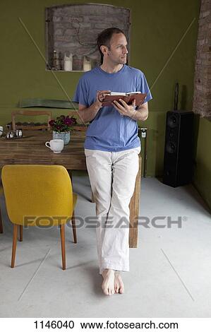 A man leaning on a dining table holding a journal and a pen, looking away View Large Photo Image Stock Image - A man leaning on a dining table holding a journal and a pen, looking away. Fotosearch
