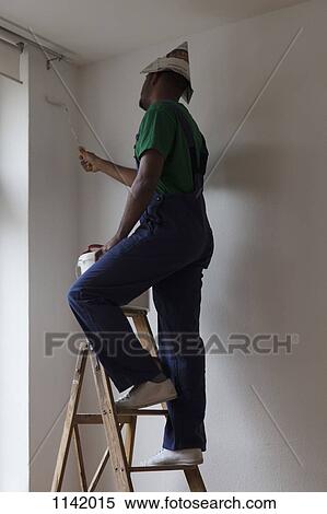 A man standing on a ladder and painting a wall View Large Photo Image Stock Photography - A man standing on a ladder and painting a wall. Fotosearch