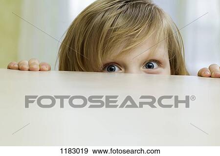 A mischievous girl peeking over the top of a table View Large Photo Image Stock Photo - A mischievous girl peeking over the top of a table. Fotosearch