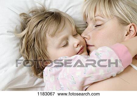 Stock Photo - A mother and her young daughter sleeping a bed side by side. Fotosearch