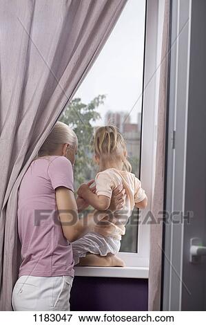 A mother and young daughter looking out their home window View Large Photo Image Stock Photo - A mother and young daughter looking out their home window. Fotosearch