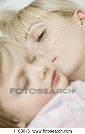 Stock Photograph - A mother waking up next to her sleeping child. Fotosearch