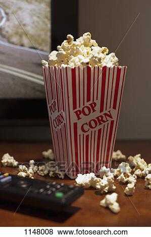 A red striped carton of popcorn on a table in front of a flat screen TV View Large Photo Image Stock Photo - A red striped carton of popcorn on a table in front of a flat screen TV. Fotosearch
