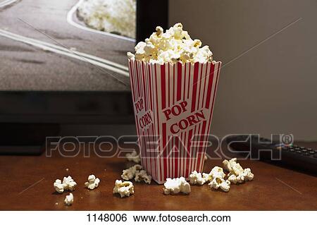 A red striped carton of popcorn on a table in front of a flat screen TV View Large Photo Image Stock Photograph - A red striped carton of popcorn on a table in front of a flat screen TV. Fotosearch