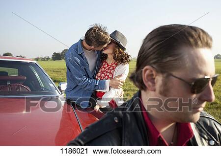 A rockabilly couple kissing while leaning on a vintage car, man in foreground View Large Photo Image Stock Image - A rockabilly couple kissing while leaning on a vintage car, man in foreground. Fotosearch