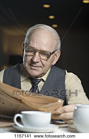 A senior man reading a newspaper in a cafe View Large Photo Image Stock Image - A senior man reading a newspaper in a cafe. Fotosearch