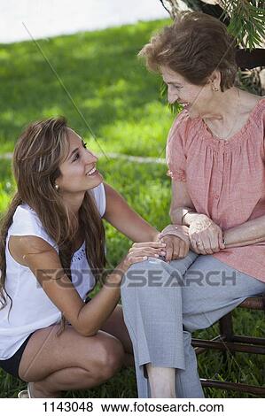 A senior woman and a young woman sitting together outside View Large Photo Image Stock Photo - A senior woman and a young woman sitting together outside. Fotosearch