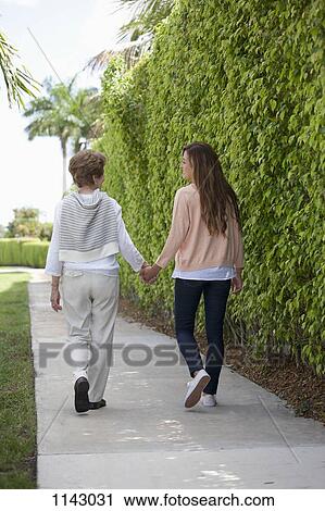 A senior woman and a young women holding hands and walking together View Large Photo Image Stock Image - A senior woman and a young women holding hands and walking together. Fotosearch