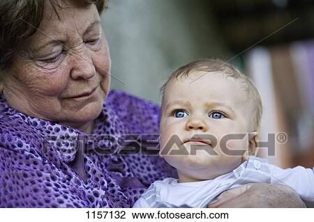 A senior woman holding a baby View Large Photo Image Stock Image - A senior woman holding a baby. Fotosearch